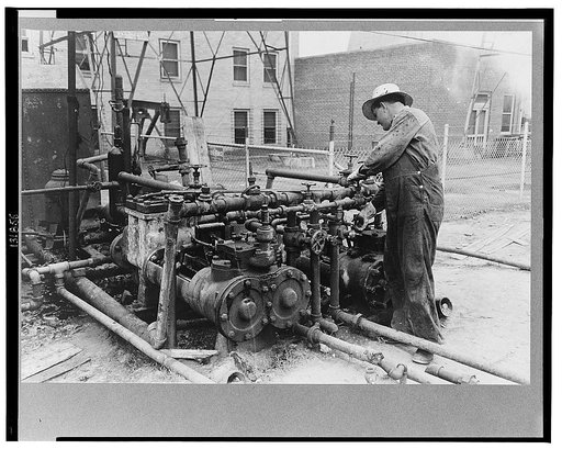 Oil field worker working on the mud hog, a machine which pumps the mud from the sluch pit through the drill pipe to the bit, Kilgore, Texas