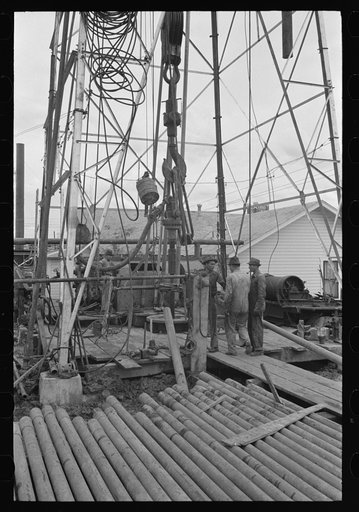 Detail of derrick showing traveling block, kelly joint, rotary table and lengths of drill pipe, Kilgore, Texas