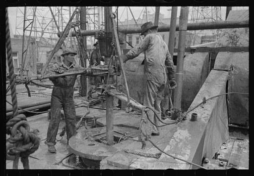 Untitled photo, possibly related to: Oil field workers adding a length of pipe to drill stream by means of heavy pipe wrenches, Kilgore, Texas