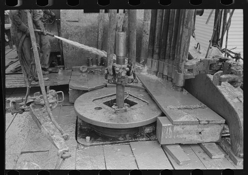 Rotary table, links and clamps of elevator with sections of pipe, oil well, Kilgore, Texas