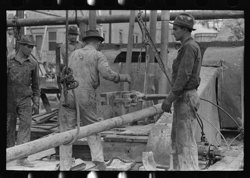 Untitled photo, possibly related to: Oil field workers releasing pipe wrenches from drill pipe, oil well, Kilgore, Texas