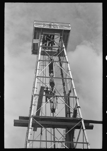 Top of derrick showing gin pole, crow's nest, crown block, traveling block, elevator and cat line. Oil well, Kilgore, Texas