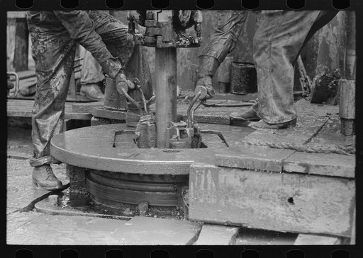 Removing clamps from rotary tacle before lifting out drilling pipe, oil well, Kilgore, Texas