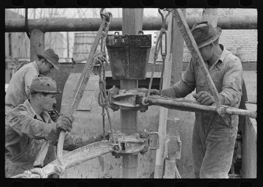 Screwing one length of pipe to another by means of pipe wrenches, oil well, Kilgore, Texas