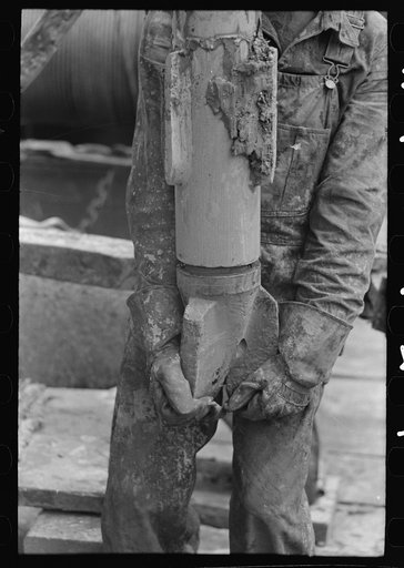 Oil field worker holding bit, oil well, Kilgore, Texas