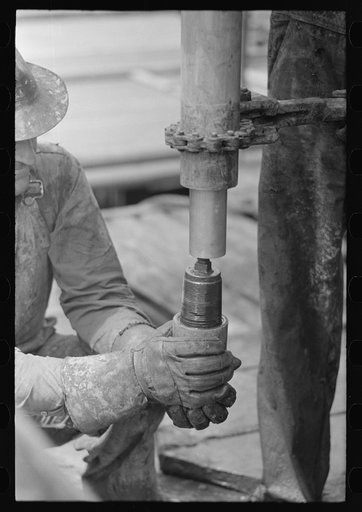 Oil field worker screwing on a nipple, Kilgore, Texas