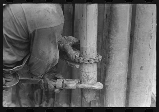 Tightening the nipple on the end of drill pipe oil field, Kilgore, Texas. This part of operation to determine direction and draft of drilling