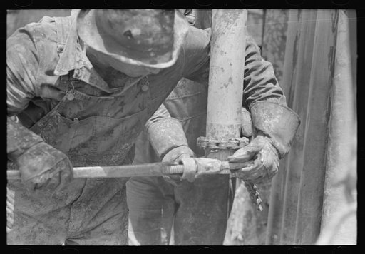Untitled photo, possibly related to: Tightening the nipple on the end of drill pipe oil field, Kilgore, Texas. This part of operation to determine direction and draft of drilling
