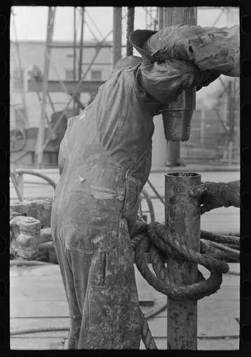 Detail of screwing one pipe into another. Oil field drilling operations, Kilgore, Texas