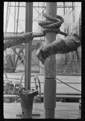 Untitled photo, possibly related to: Detail of screwing one pipe into another. Oil field drilling operations, Kilgore, Texas