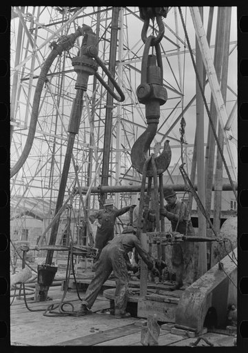 Activity at oil well showing one length of pipe resting on the kelly joint into the rat hole with operations for removing other lengths of pipe from the hole. Oil well, Kilgore, Texas