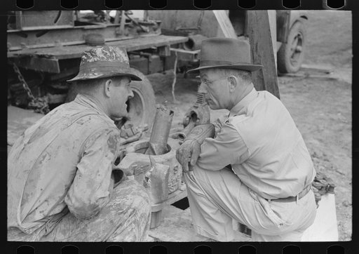 Untitled photo, possibly related to: Oil field workers squatting down while talking to bit salesman, Kilgore, Texas