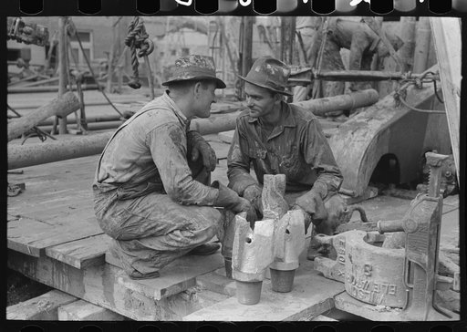 Oil field workers talking together with bits in front of them, Kilgore, Texas