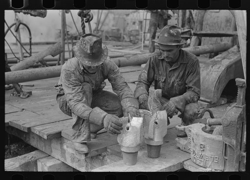 Untitled photo, possibly related to: Oil field workers talking together with bits in front of them, Kilgore, Texas