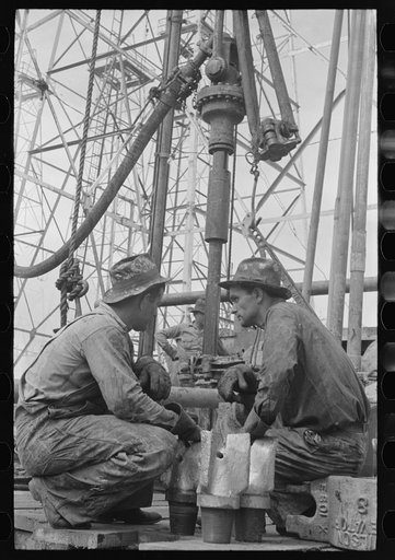 Untitled photo, possibly related to: Oil drillers talking with bits in front of them and drilling equipment in background, Kilgore, Texas