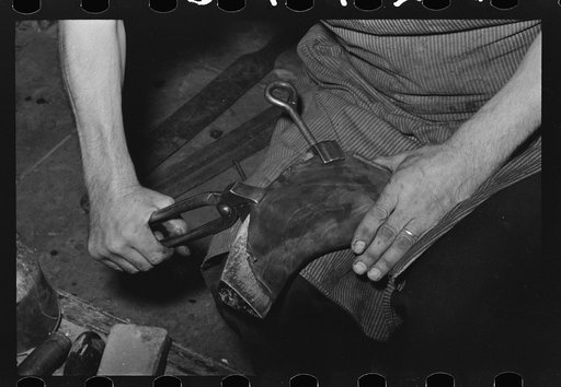 Shaping piece of leather over wooden form to make foot of boot. Bootmaking shop, Alpine, Texas