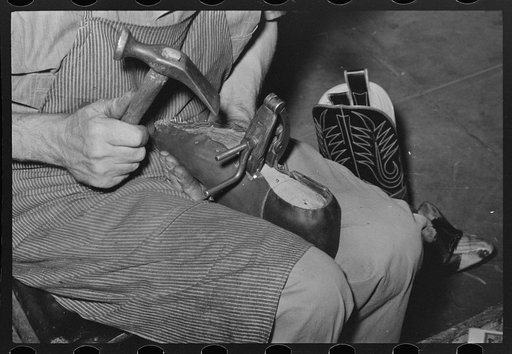 Nailing foot of boot to sole, in order to hold in place when sewing foot to welt. These nails are removed after sewing. Bootmaking shop, Alpine, Texas