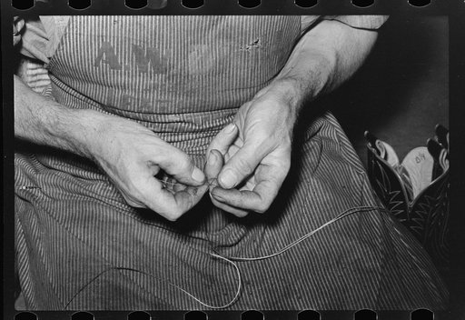 Threading a needle with waxed thread. Bootmaking shop, Alpine, Texas