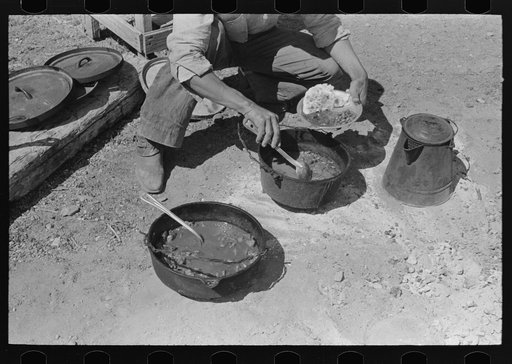 Cowboy dishing up chili at noonday dinner. Cattle ranch near Marfa, Texas