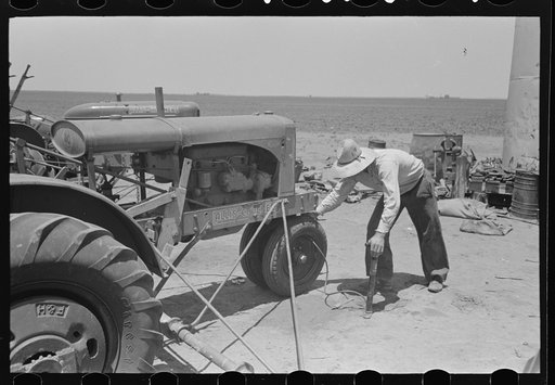Day laborer pumping up tire on tractor on large farm near Ralls, Texas. Nine tractors were used on this farm of four thousand nine hundred acres