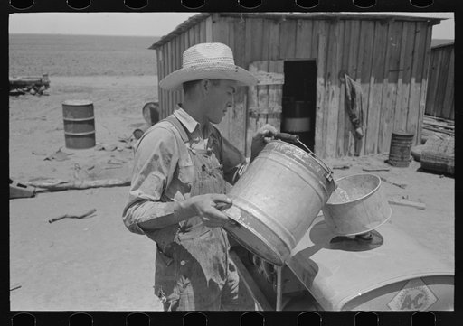 Untitled photo, possibly related to: Pouring gasoline into tractor, large farm near Ralls, Texas. Man is day laborer