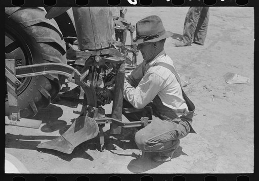 Day laborer changing plow points on four-row planter, farm near Ralls, Texas