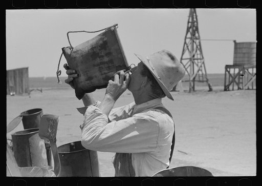 Day laborer drinking from desert water bag, large farm near Ralls, Texas