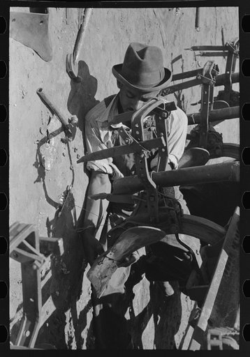 Negro day laborer adjusting plow points on cotton planter, large farm near Ralls, Texas