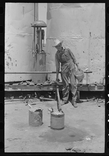 Day laborer filling five gallon cans with gasoline for use in tractors, large farm near Ralls, Texas