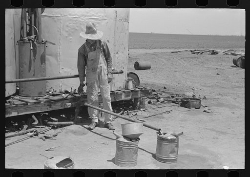 Untitled photo, possibly related to: Day laborer filling five gallon cans with gasoline for use in tractors, large farm near Ralls, Texas