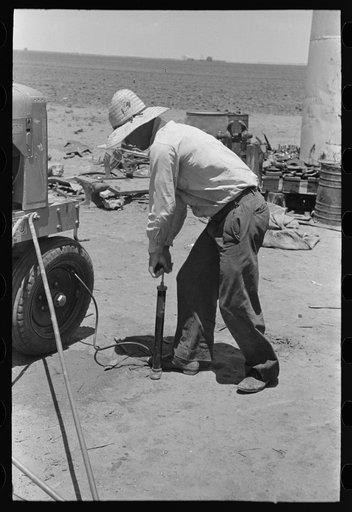 Untitled photo, possibly related to: Day laborer pumping up tractor tire, farm near Ralls, Texas