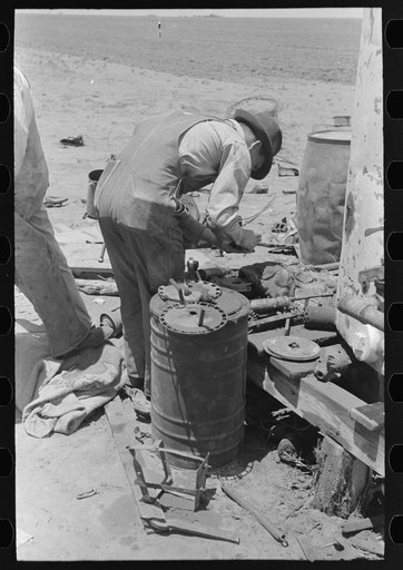 Untitled photo, possibly related to: Day laborer adjusting plow points on tractor-drawn planter, farm near Ralls, Texas