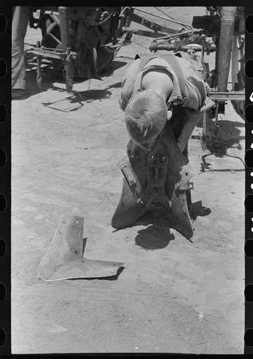 Untitled photo, possibly related to: Day laborer adjusting plow points on tractor-drawn planter, farm near Ralls, Texas