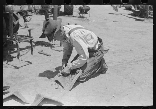 Day laborer adjusting plow points on tractor-drawn planter, farm near Ralls, Texas