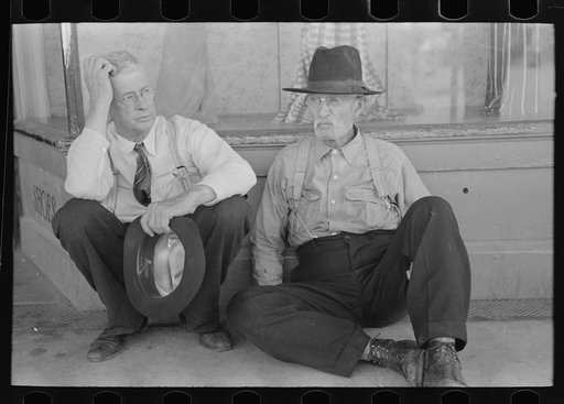 Farmers sitting against wall and squatting on sidewalk, Spur, Texas