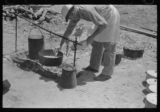 Camp cook working over an open fire, cattle ranch near Spur, Texas. The old attitude of the inferiority of the cook on the range is still prevalent. This cook said "the boys treat me awfully good"