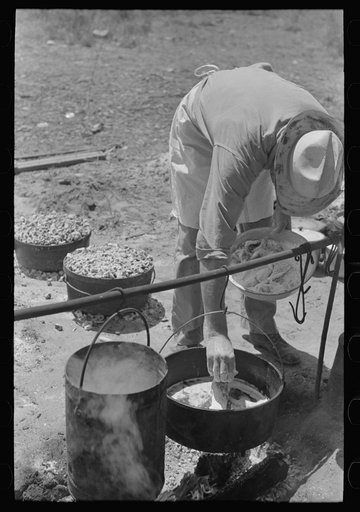 Camp cook working over an open fire, cattle ranch near Spur, Texas. The old attitude of the inferiority of the cook on the range is still prevalent. This cook said "the boys treat me awfully good."