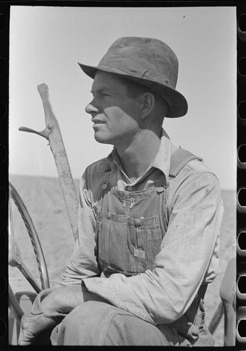 Day laborer sitting in tractor seat, large farm near Ralls, Texas