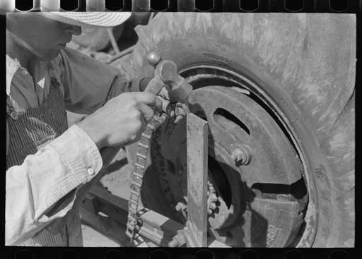 Day laborer repairing link of chain which operates planter feed, farm near Ralls, Texas