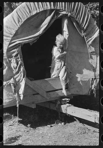 Son of white migrant stepping from covered wagon-type trailer, Wagoner County, Oklahoma