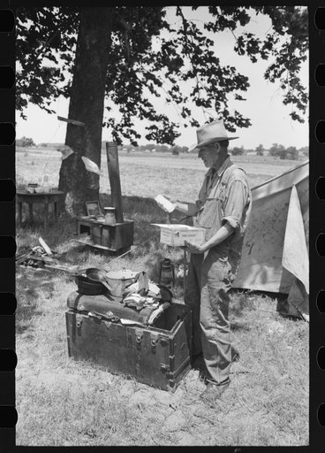 Untitled photo, possibly related to: Veteran migrant agricultural worker examining contents of his trunk, camped on Arkansas River in Wagoner County, Oklahoma
