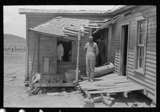 Untitled photo, possibly related to: Negro tenant farmer on his front porch. This farm is owned by an out-of-state woman and has been rented by this family of Negroes for eleven years. The Negro man says that the agent is changed so often that no one ever takes any interest in the condition of the l