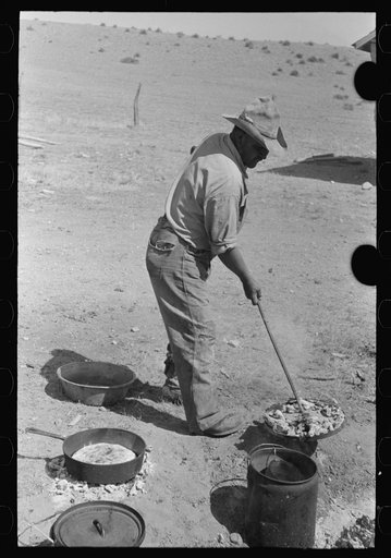 Cook lifting lid full of coals from dutch oven used for baking bread near Marfa, Texas