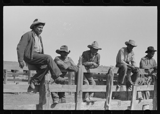 Cowboys sitting on corral fence. Roundup near Marfa, Texas