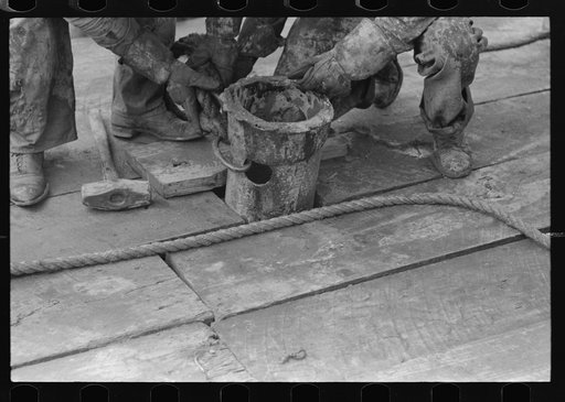 Roughnecks guiding bailer into hole during bailing out operations, oil well, near Seminole, Oklahoma. They were bailing out mud and water in old well before drilling to a deeper level