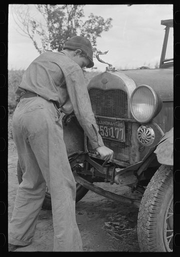 Migrant boy getting ready to crank his car, Muskogee, Oklahoma
