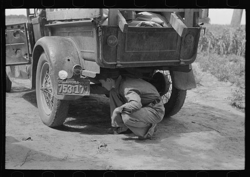 Examining brakes of car which will take this family to California near Muskogee, Oklahoma
