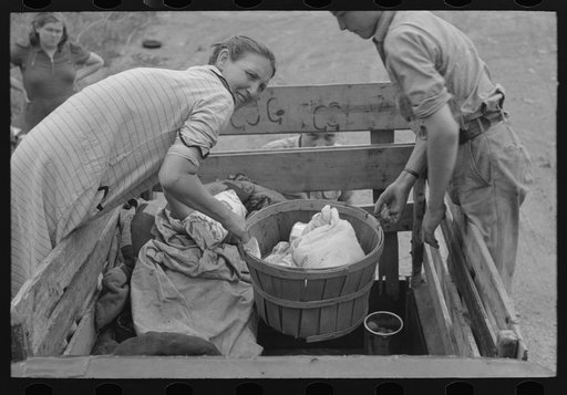 Removing victuals and groceries from the improvised truck at campfire near Henrietta [i.e., Henryetta,] Oklahoma. This is a migrant family en route to California