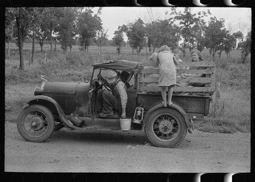 Migrant getting out of car with pail to get some water. Encamped along roadside near Henrietta [i.e., Henryetta,] Oklahoma
