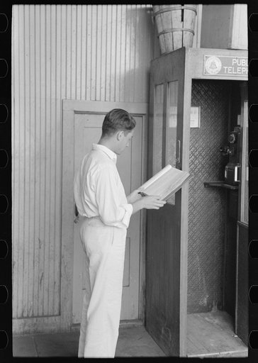Untitled photo, possibly related to: Man looking up telephone number. Streetcar terminal, Oklahoma City, Oklahoma